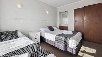 Habitación de hotel con dos camas, un armario de madera, una cómoda blanca y un espejo.