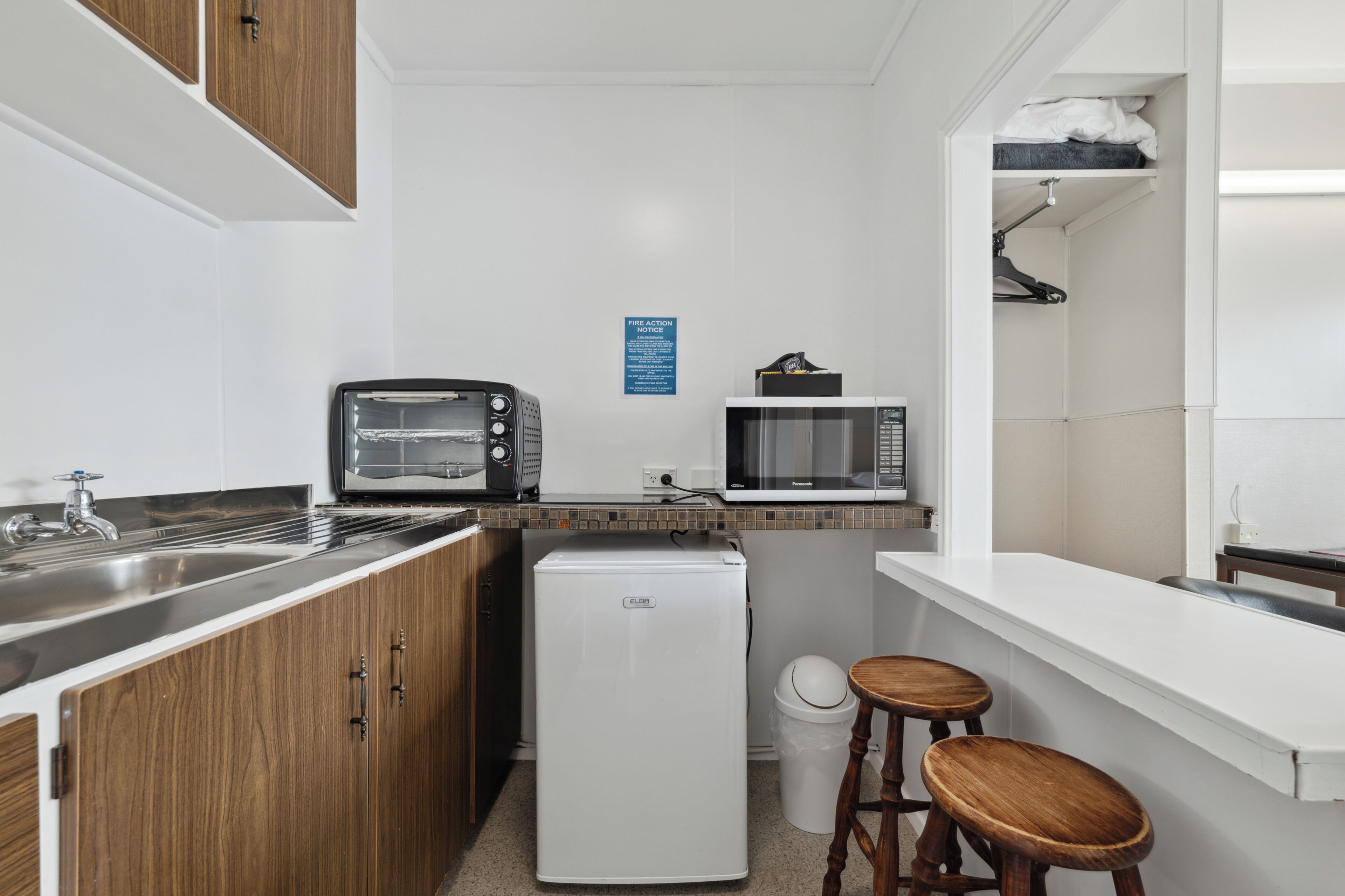 A compact kitchenette with a refrigerator, microwave, toaster, and sink.