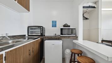 A compact kitchenette with a refrigerator, microwave, toaster, and sink.