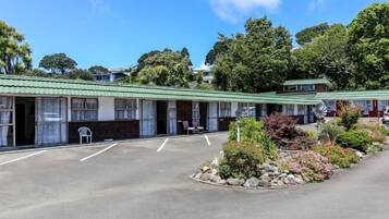 A motel with a green roof, multiple rooms, and a parking lot.