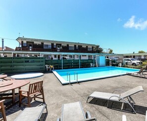 Relax by the pool with lounge chairs and a small table for a peaceful retreat.