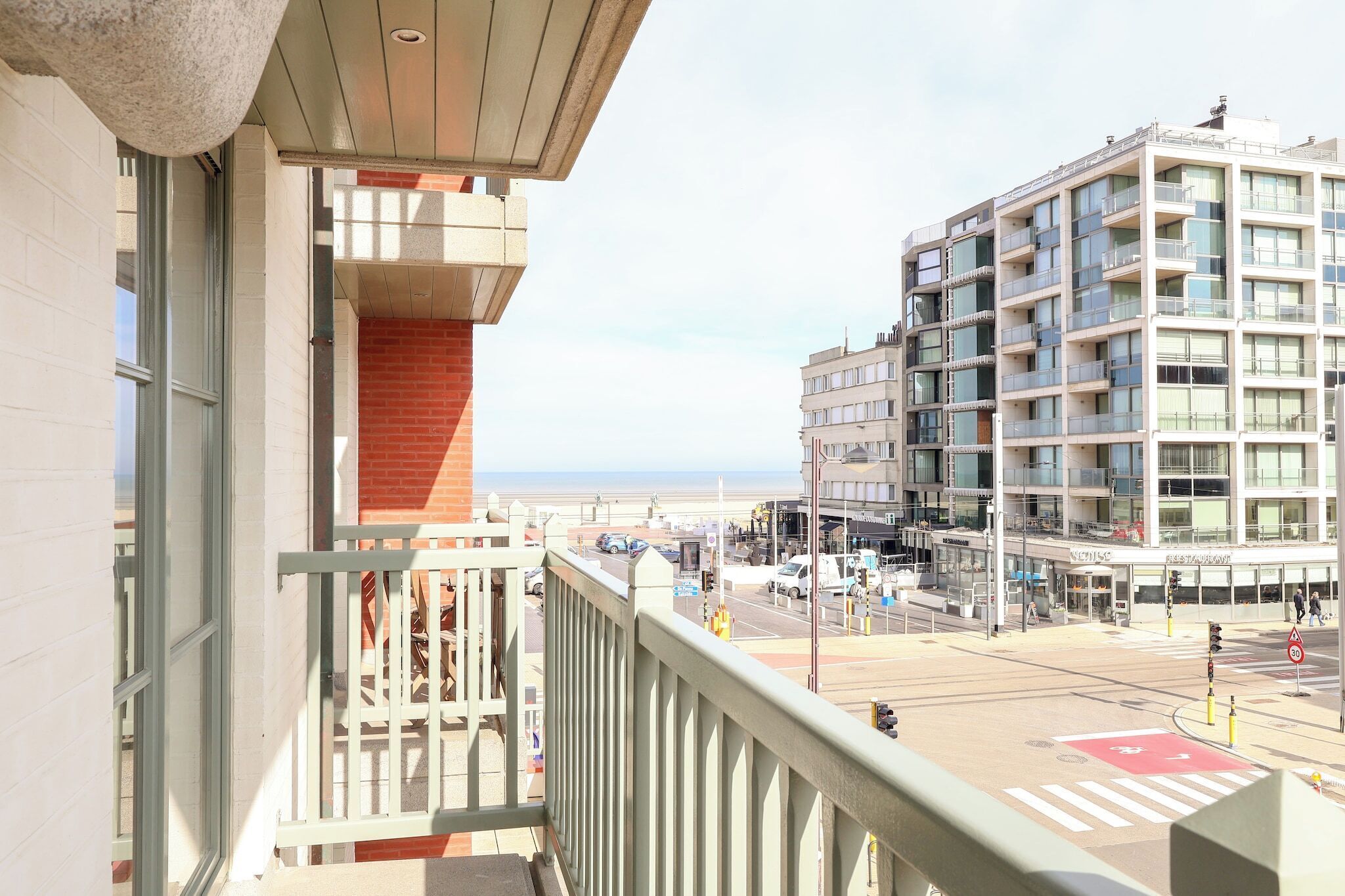 A balcony with a view of a modern building and a street.