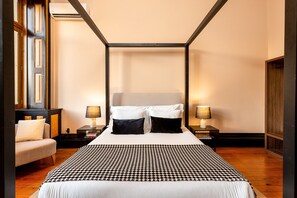 A bedroom with a large bed, two bedside tables with lamps, a chair, and a wooden floor. - Spacious Modern Apartment in Porto (Oporto)
