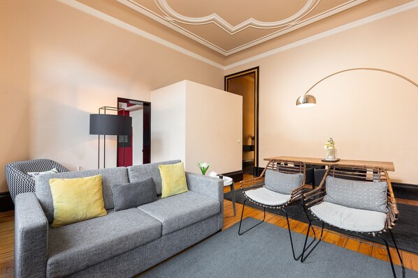 A modern living room with a grey sofa, two armchairs, a small table, and a lamp. - Spacious Modern Apartment in Porto (Oporto)