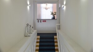A staircase with a dark carpet leading to a door with a sign reading "BOCA DE INCENDIO".