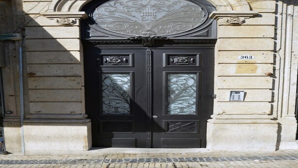 A double door with intricate glass designs and a number plaque.