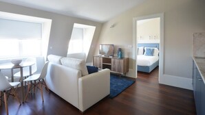 A modern, well-lit living room with a sofa, dining table, and TV. - Porto Retreat: Comfort & Style in the Heart (Oporto)
