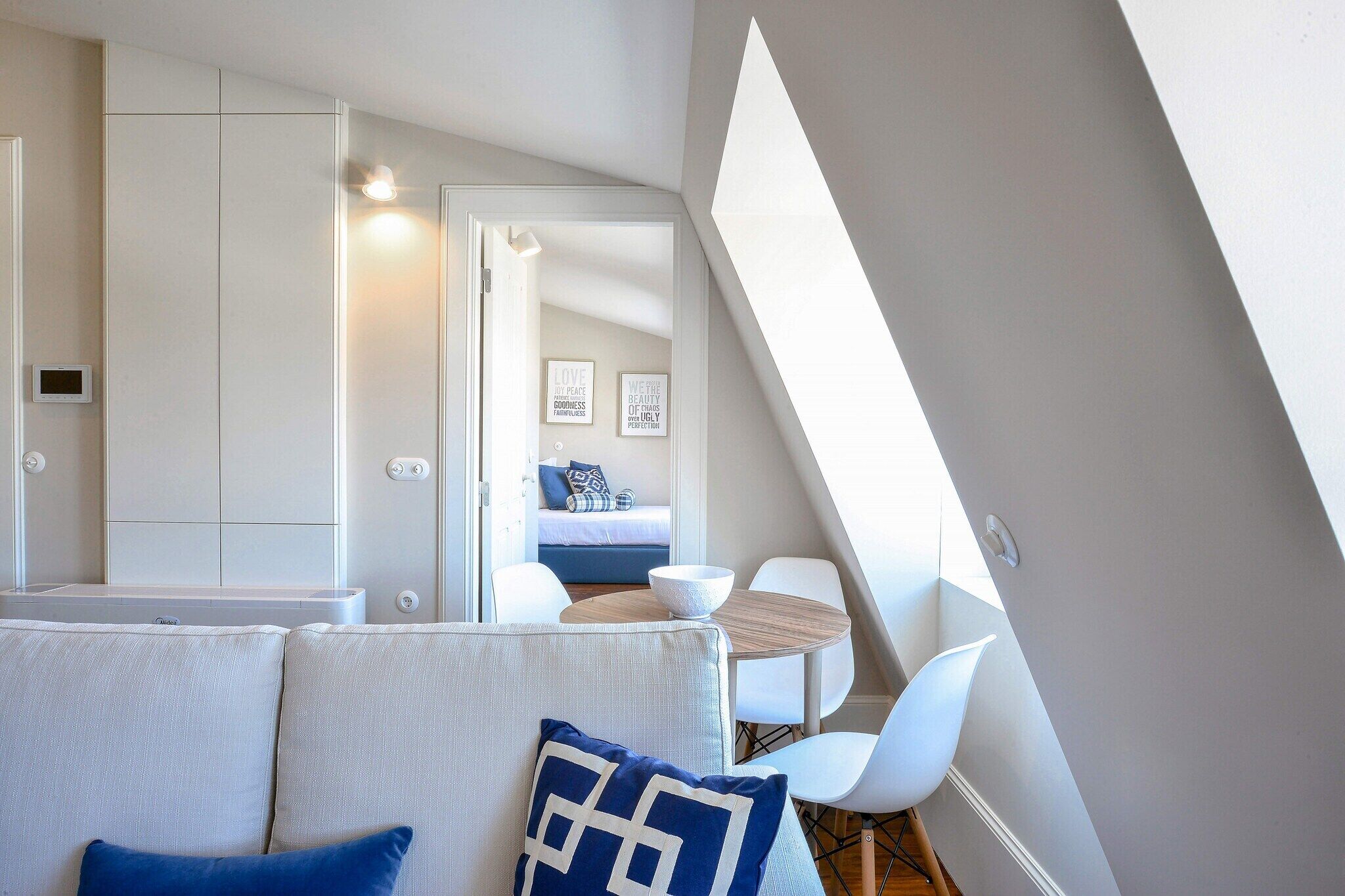 A modern, compact living space with a loft bedroom, a dining area, and a kitchenette.