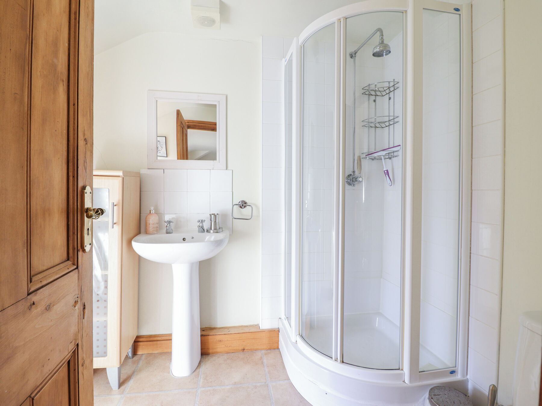 Une salle de bain avec un lavabo blanc, un miroir et une douche à parois de verre.