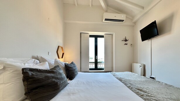 A bedroom with a bed, a TV mounted on the wall, and an air conditioning unit. - Charming 2-Bedroom Apartment in Porto (Oporto)