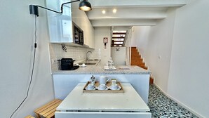 A compact kitchen with a countertop, a coffee machine, a kettle, and a tray with cups and a teapot. - Charming 2-Bedroom Apartment in Porto (Oporto)
