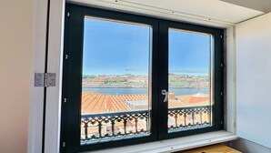 A window with a view of a cityscape, including buildings and a bridge. - Charming 2-Bedroom Apartment in Porto (Oporto)