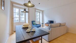 A modern living room with a wooden table, a blue armchair, a grey sofa, and a TV. - 1-bedroom beautiful apartment in Oporto (Oporto)