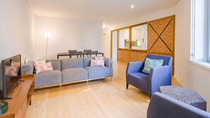 Un salon moderne avec un canapé gris, un fauteuil bleu et un mur d’accent en bois.
