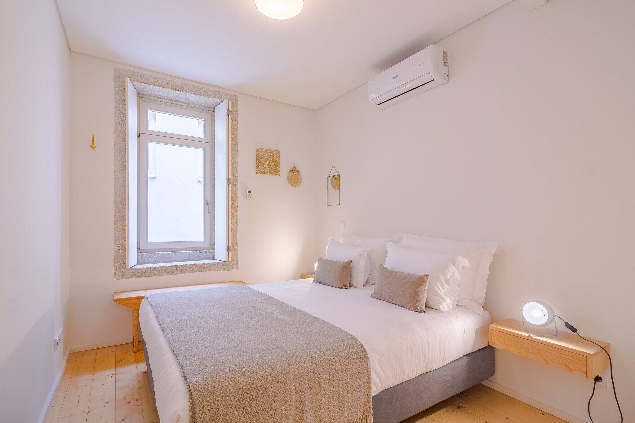 Quarto com cama, mesa de cabeceira e janela.