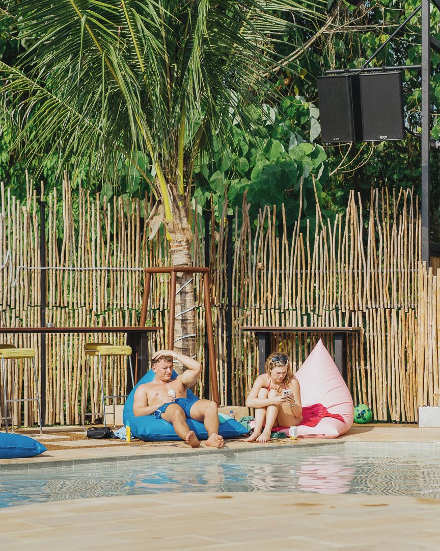 Un espace piscine agrémenté d’une clôture en bambou, de chaises longues et d’un haut-parleur.