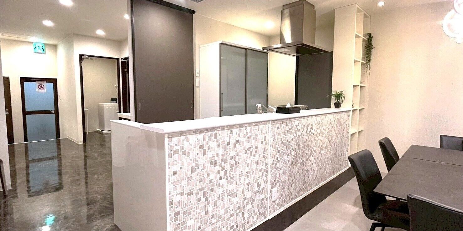 Una cocina moderna con salpicadero de azulejos, extractor de acero inoxidable y encimera con lavamanos.