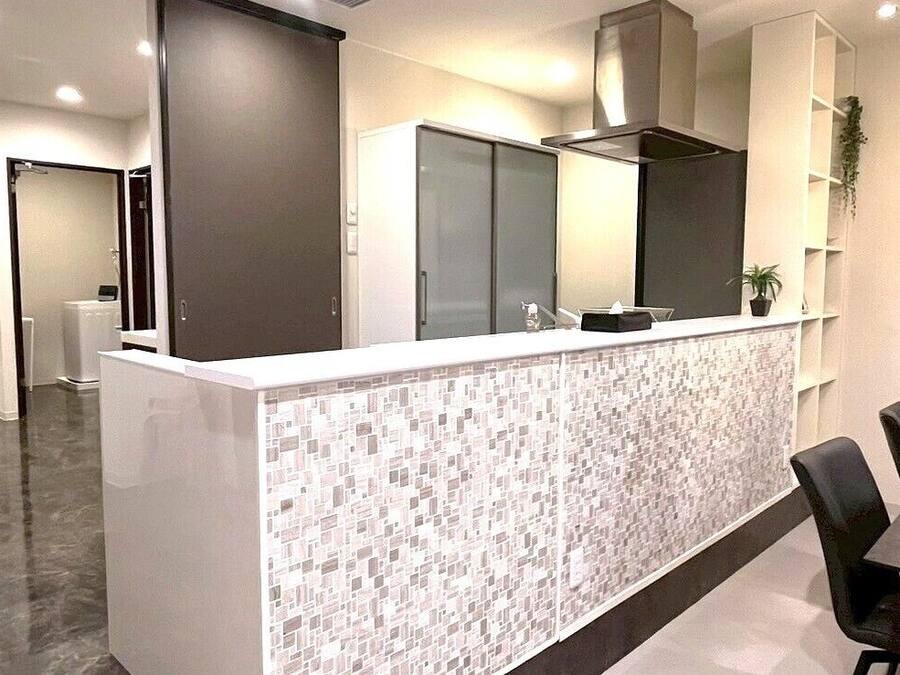 Una cocina moderna con salpicadero de azulejos, extractor de acero inoxidable y encimera con lavamanos.