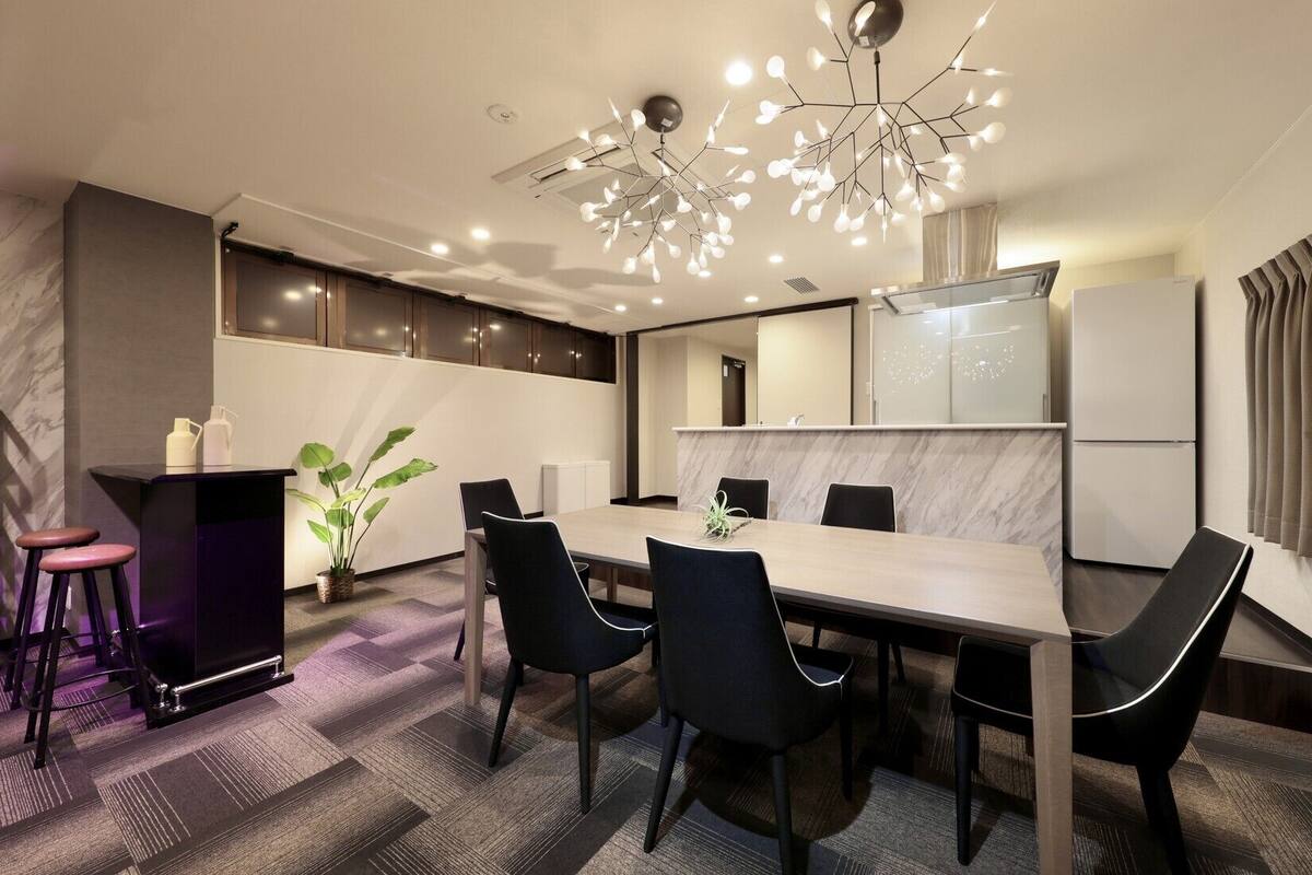 Une salle de réunion moderne dotée d’un comptoir en marbre, de chaises noires, d’une table centrale et d’un luminaire au plafond au design original.