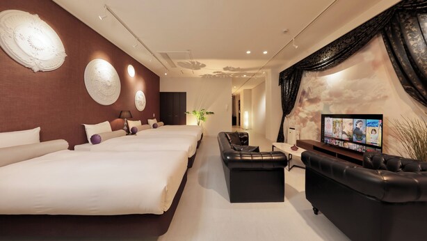 Ein modernes Hotelzimmer mit zwei großen Betten, einer schwarzen Ledersofa und einem Flachbildfernseher, ergänzt durch dekorative Wandbilder.