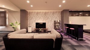 Ein modernes Wohnzimmer mit einer Couch, einem Fernseher, einem Couchtisch und einer Bar mit Hockern.