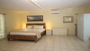 A bedroom with a wooden bed, a nightstand, a dresser, a mirror, and an air conditioning unit. - Del Haven Holiday House (ARCADIA)