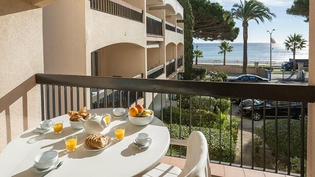 Un balcon aménagé pour le petit-déjeuner, avec des croissants, des fruits et du jus d’orange.