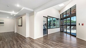 Un interior espacioso y moderno con techo alto, iluminación empotrada y grandes ventanas que ofrecen vistas a equipo de ejercicio al aire libre.