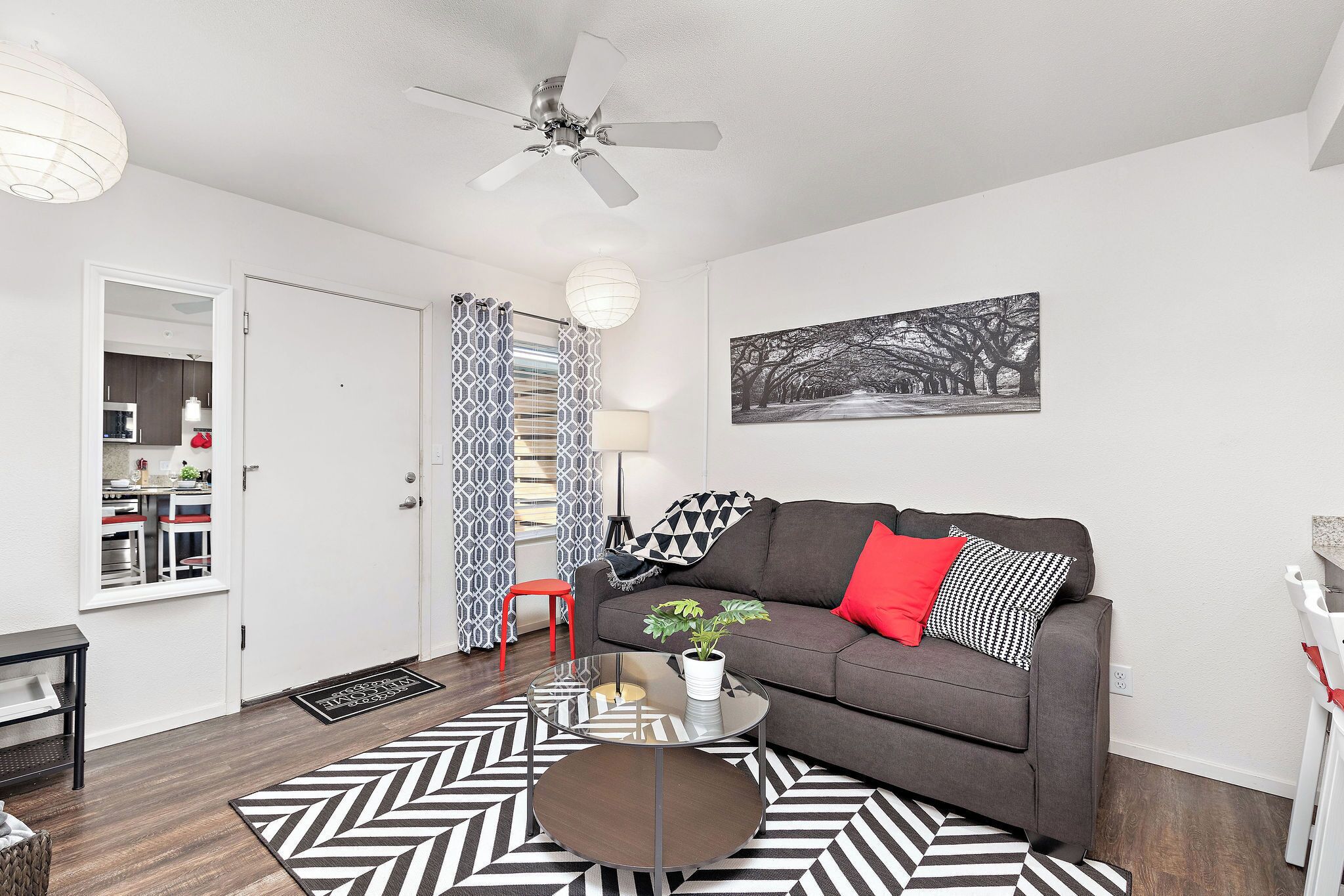 Un salon moderne avec un canapé gris, une table basse et un tapis noir et blanc.