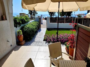 A patio area with a table and chairs, a pathway, and potted plants. - Aphrodite's Apartments (Spata-Artemida)