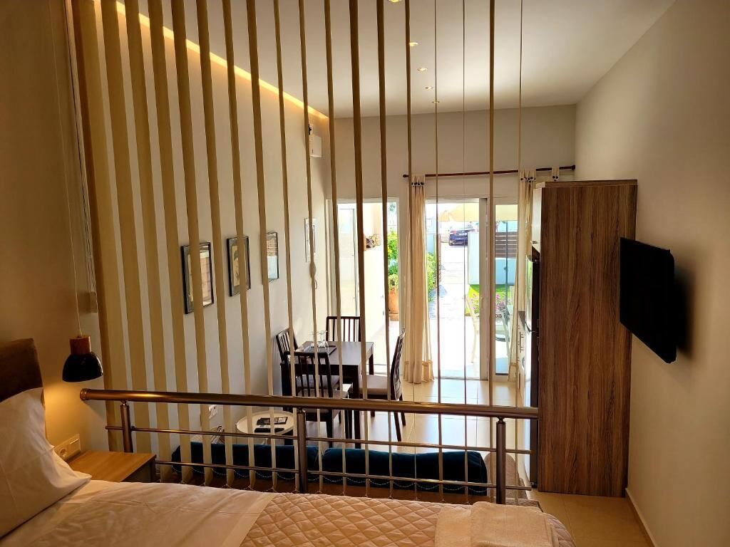 A hotel room with a bed, a desk, a chair, and a TV mounted on the wall.