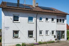 A white building with multiple windows, solar panels on the roof, and a sign reading 'Burgweg 6'. - Apartment 'Kleinert' with Shared Garden, Balcony and Wi-Fi (Blaufelden-Billingsbach)