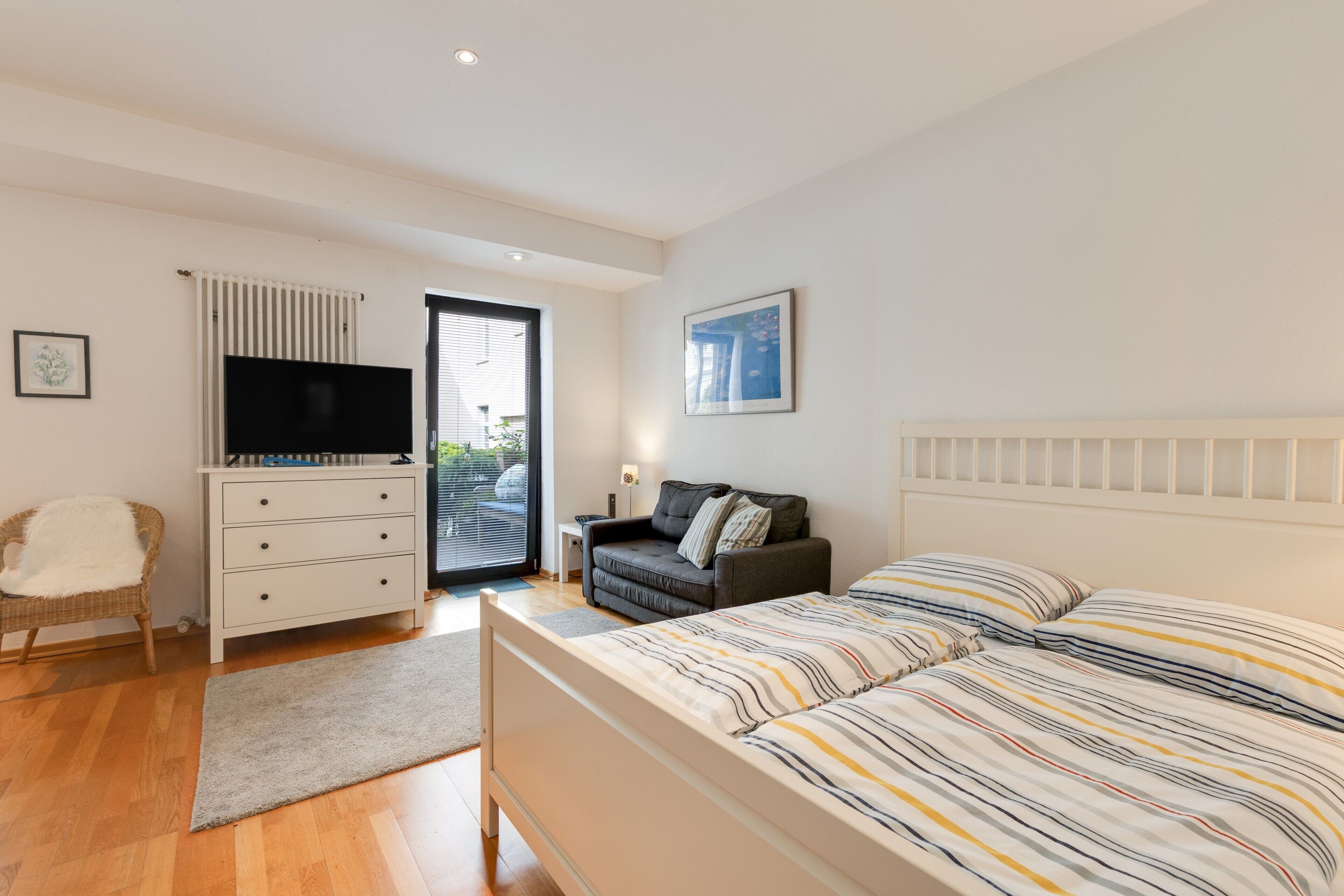 Ein Schlafzimmer mit Bett, Fernseher, Sofa und Kommode.