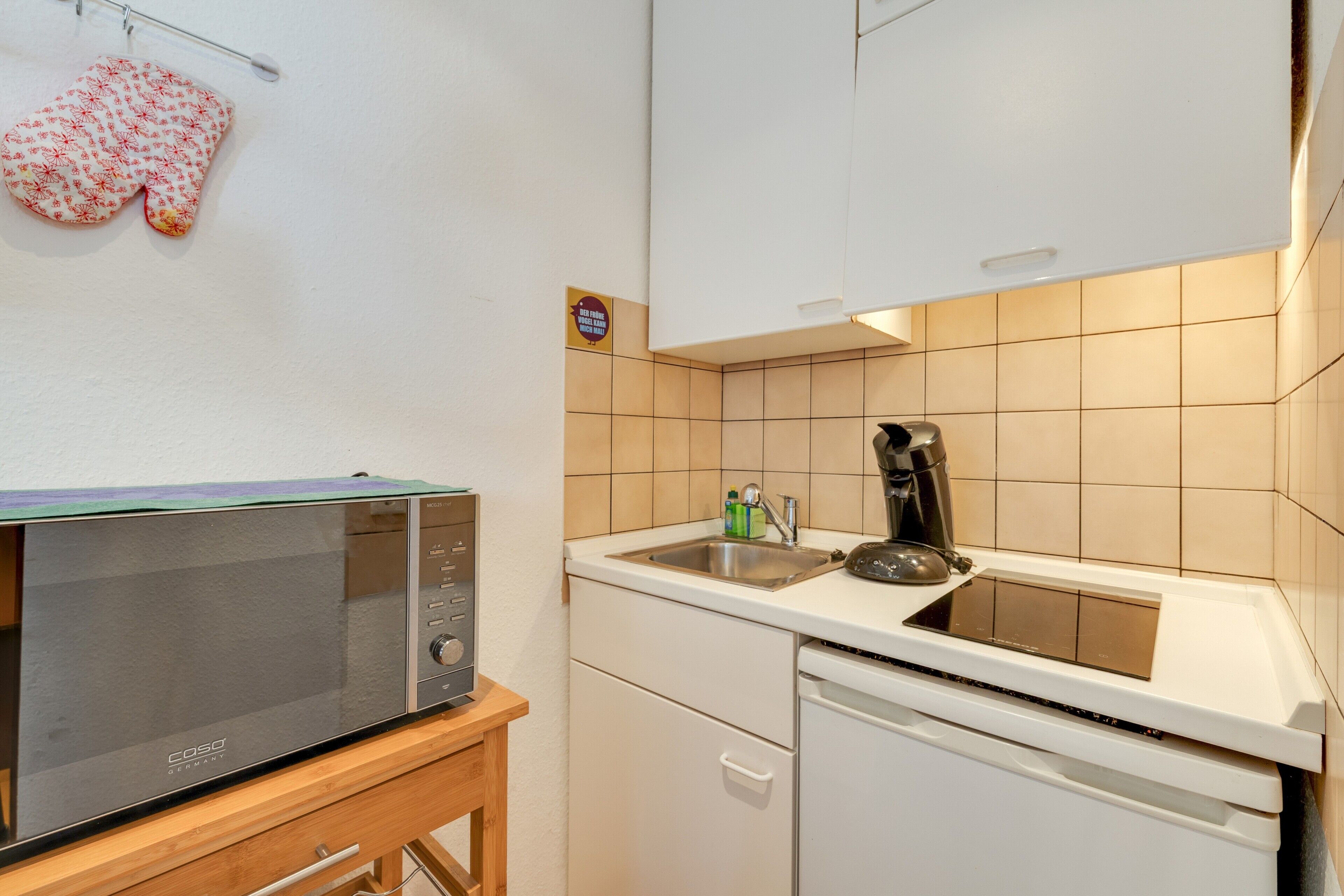 Eine kompakte Küche mit Mikrowelle, Kaffeemaschine und Geschirrspüler.