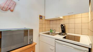 Eine kompakte Küche mit Mikrowelle, Kaffeemaschine und Geschirrspüler.