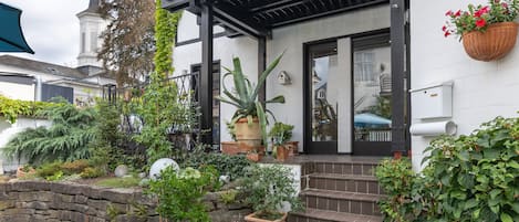 Et hus med en veranda, plantekrukker og en stenvæg.