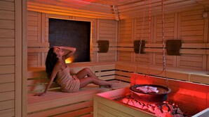 A sauna room with wooden benches and a central heating element.