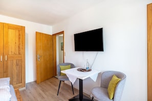 Una habitación con una cama, una mesa con televisor y dos sillas.