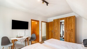 Ein Schlafzimmer mit zwei Betten, einem Schreibtisch mit Stuhl, einem Fernseher und Holzschränken.
