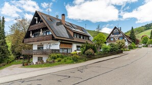 Ein traditionelles Chalet mit geneigtem Dach, Solaranlage und einem Balkon.