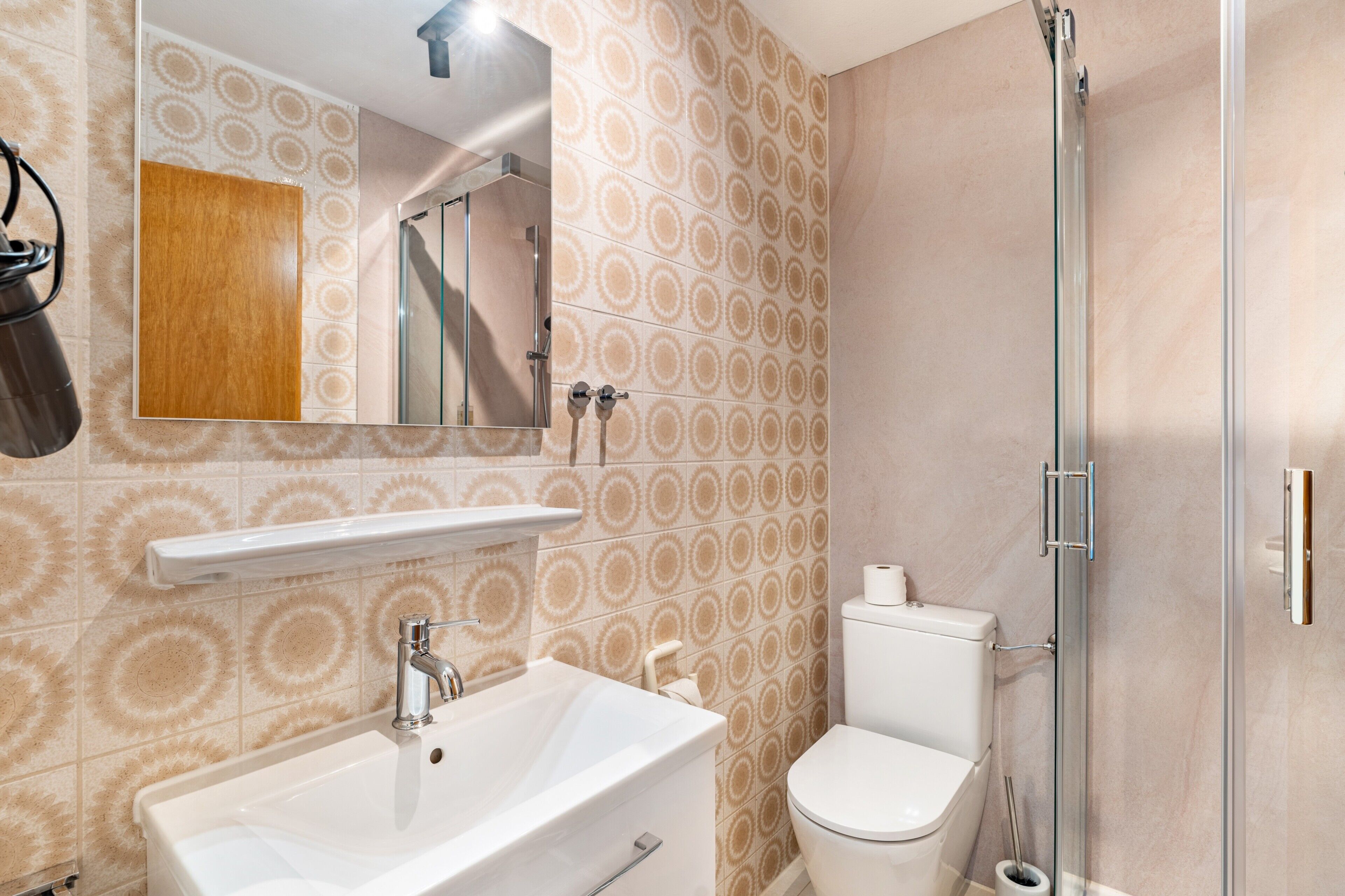 Une salle de bain équipée d’un lavabo, de toilettes, d’une douche et d’un miroir.