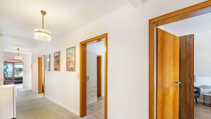Ein Flur mit Holztüren, einer weißen Wand und einem Kronleuchter.