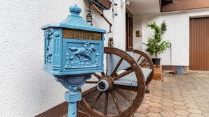 A blue mailbox with 'BRIEFE' on it, a wooden cart, and a white wall with a door in the background. - Room 'No. 5' with Shared Garden and Wi-Fi (Sasbachwalden)