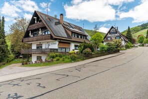 A traditional chalet-style house with a sloped roof, solar panels, and a balcony.