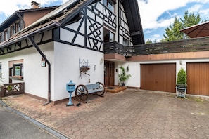 A traditional half-timbered building with a wooden door, a bench, and a potted plant.