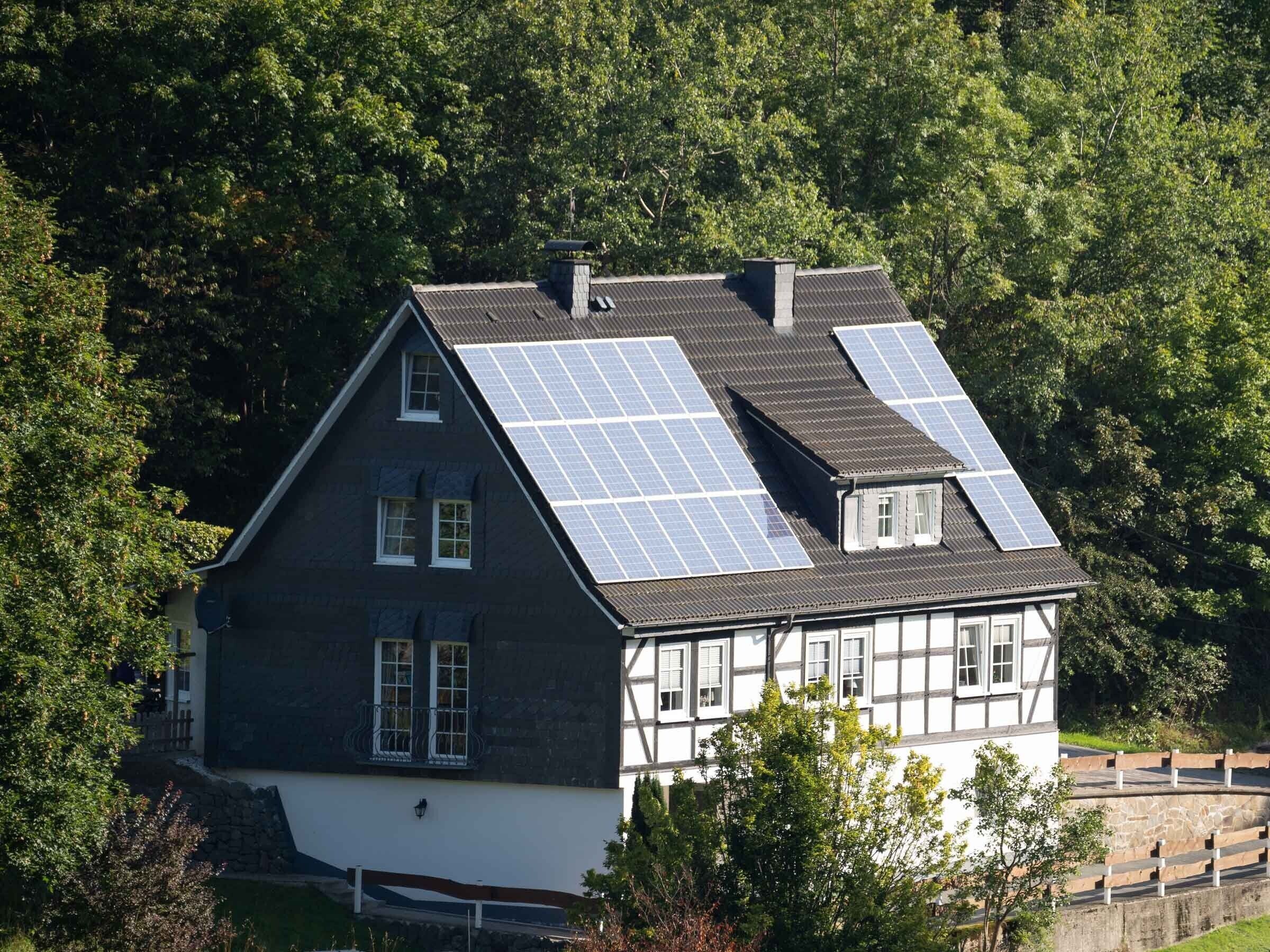A house with solar panels on the roof, surrounded by trees.