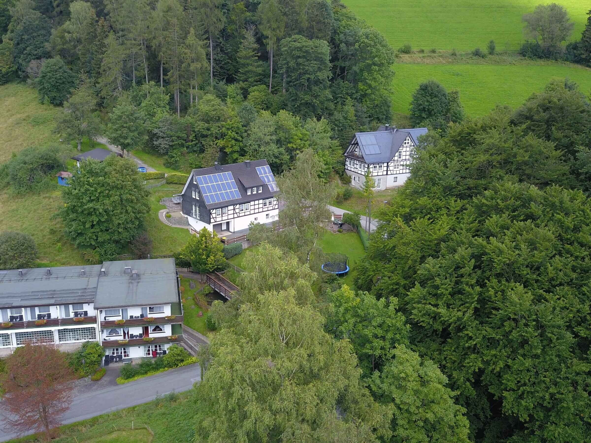 Ein ländliches Haus mit Solaranlage, umgeben von üppiger Vegetation und einem kleinen Garten.