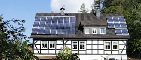 A traditional half-timbered house with solar panels on the roof.