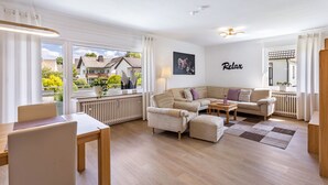 A modern living room with a sofa, armchairs, a small table, and a view of the outside. - Apartment 'Annes Stübchen' with Balcony and Wi-Fi (Schmallenberg)