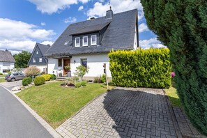 A two-story house with a grey roof, a front porch, and a well-maintained lawn. - Apartment 'Annes Stübchen' with Balcony and Wi-Fi (Schmallenberg)